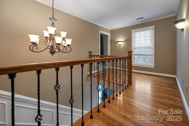 corridor with baseboards, visible vents, wood finished floors, and ornamental molding