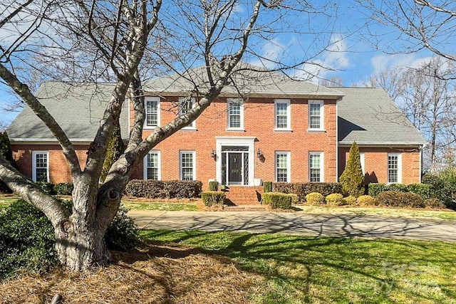 colonial home featuring a front yard and brick siding