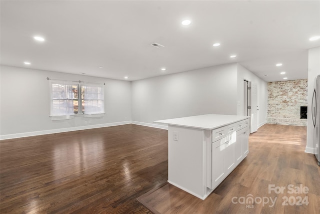 kitchen featuring a fireplace, white cabinetry, a center island, and dark wood-type flooring