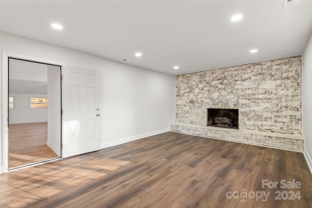 unfurnished living room with a large fireplace and dark wood-type flooring