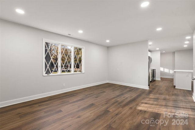 basement featuring stainless steel refrigerator and dark wood-type flooring