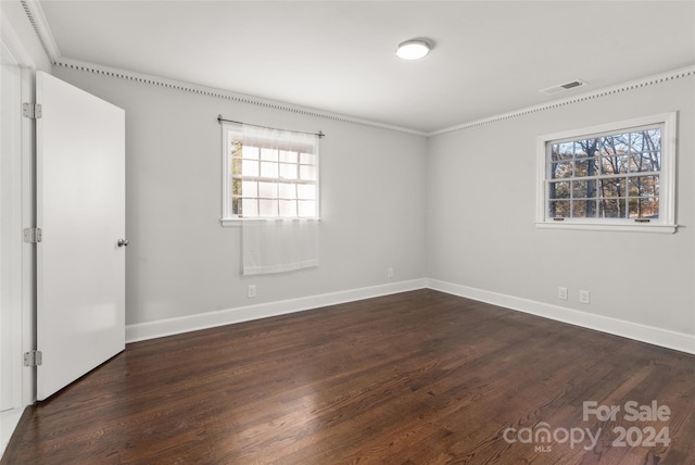 spare room featuring crown molding and dark hardwood / wood-style flooring