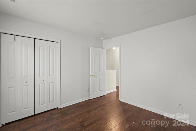 unfurnished bedroom featuring dark wood-type flooring and a closet