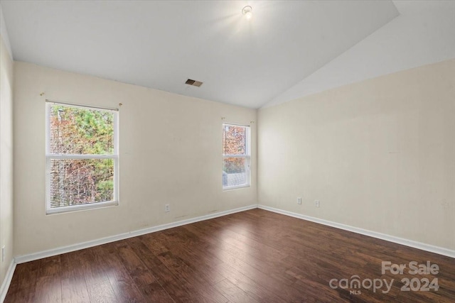 empty room with dark hardwood / wood-style floors and vaulted ceiling