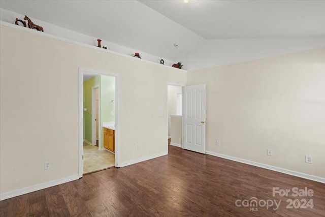 spare room featuring wood-type flooring and vaulted ceiling