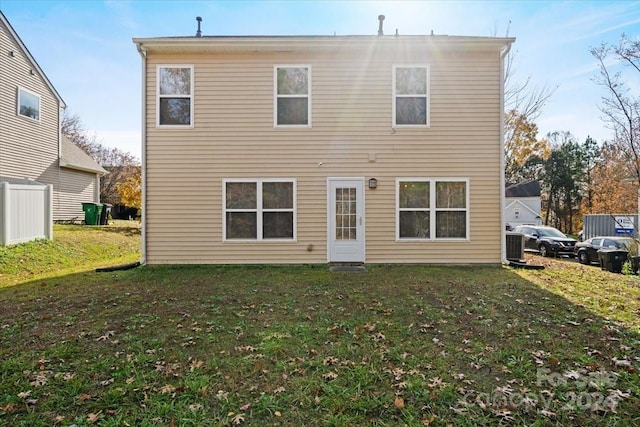 back of property with a yard and central AC