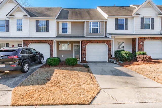 view of property with driveway, an attached garage, and brick siding