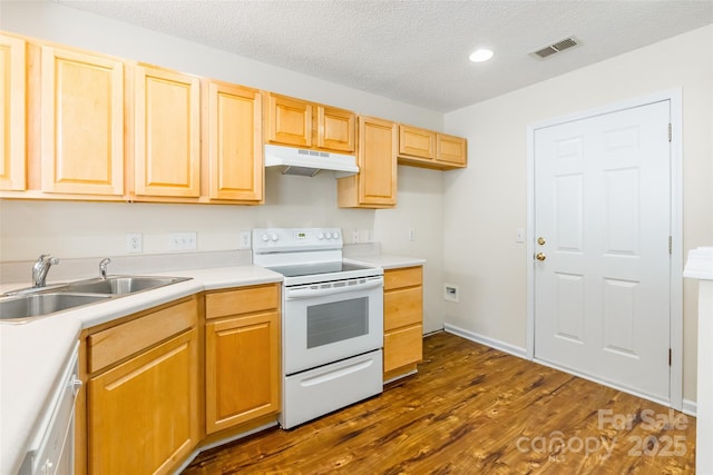 kitchen with under cabinet range hood, white appliances, a sink, visible vents, and dark wood finished floors