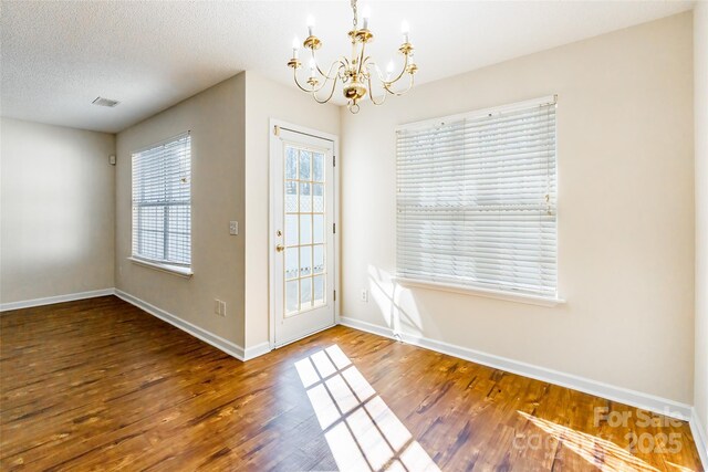 entryway with an inviting chandelier, a textured ceiling, baseboards, and wood finished floors