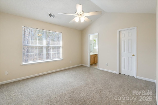 unfurnished bedroom featuring ensuite bathroom, lofted ceiling, light carpet, visible vents, and baseboards