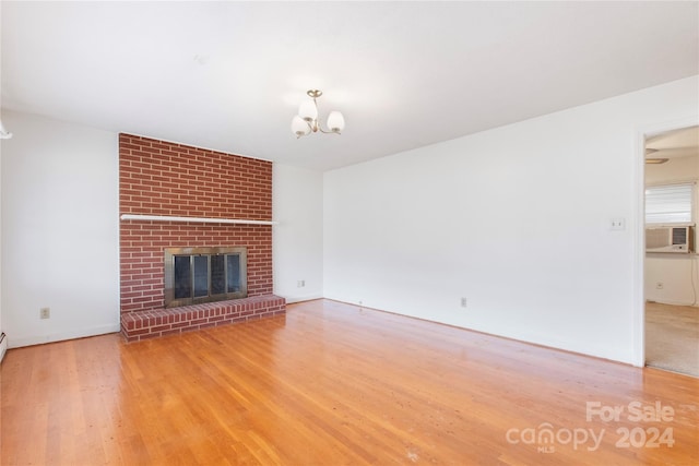 unfurnished living room featuring a fireplace, hardwood / wood-style flooring, a chandelier, and cooling unit