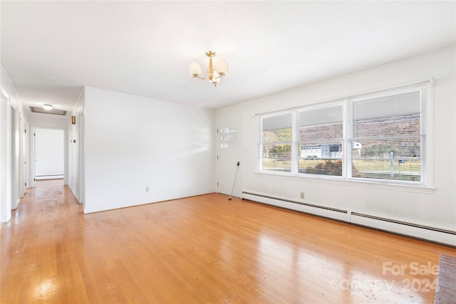 spare room featuring an inviting chandelier, light hardwood / wood-style floors, and a baseboard radiator