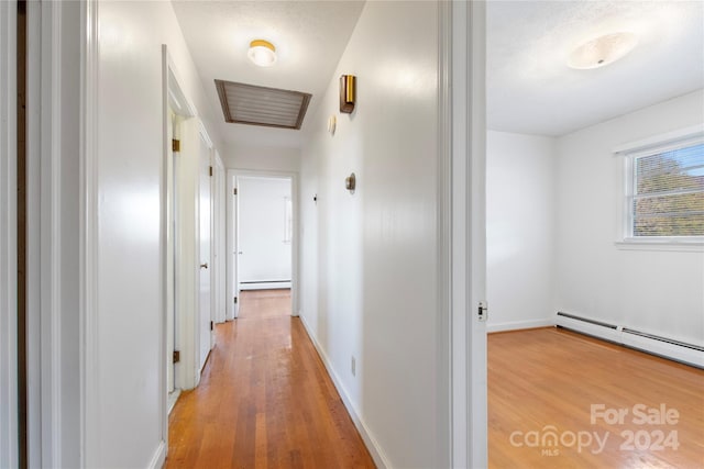 hall featuring wood-type flooring and a baseboard heating unit