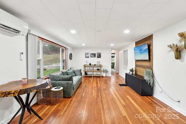 living room featuring hardwood / wood-style floors and an AC wall unit