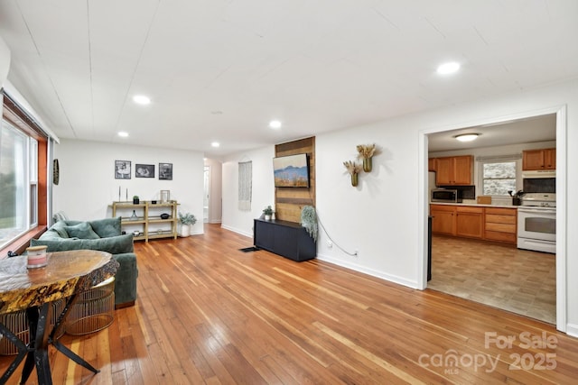 living room featuring a healthy amount of sunlight, light wood finished floors, baseboards, and recessed lighting