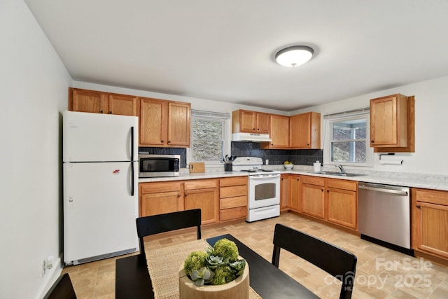 kitchen with appliances with stainless steel finishes, plenty of natural light, a sink, and under cabinet range hood