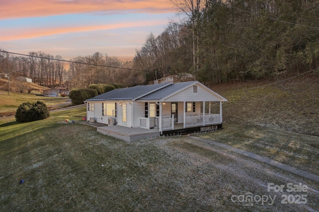 view of front of house featuring a yard, covered porch, and metal roof