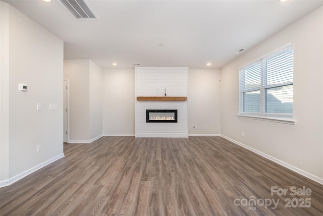 unfurnished living room with dark hardwood / wood-style flooring and a large fireplace