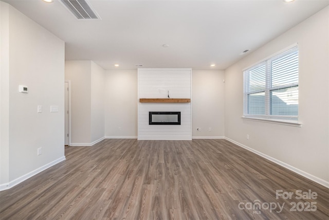 unfurnished living room featuring a fireplace and dark wood-type flooring