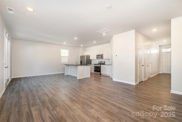 kitchen with a center island with sink, sink, dark hardwood / wood-style flooring, white cabinetry, and stainless steel appliances