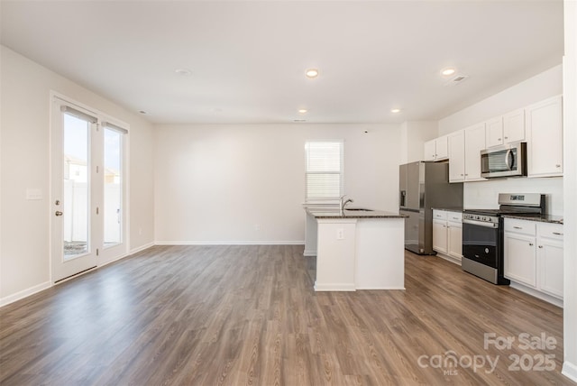 kitchen with a center island with sink, hardwood / wood-style flooring, plenty of natural light, white cabinetry, and stainless steel appliances