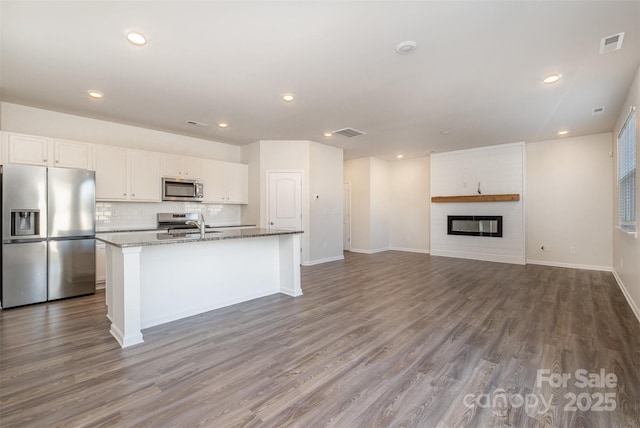 kitchen featuring white cabinetry, light stone countertops, a kitchen island with sink, and appliances with stainless steel finishes