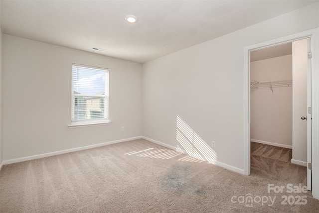 unfurnished bedroom with carpet flooring, a walk in closet, and a closet