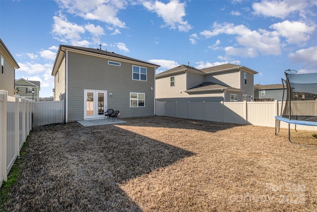 rear view of property featuring a trampoline, a patio, and french doors