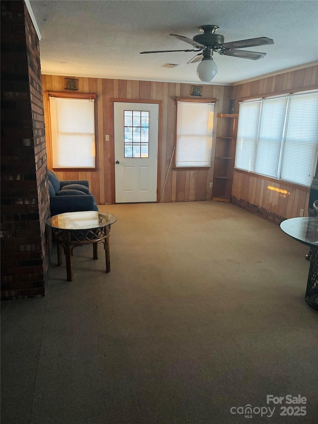 sitting room featuring ceiling fan, carpet, and a textured ceiling