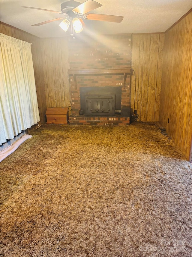 unfurnished living room featuring ceiling fan, wood walls, carpet floors, and a wood stove