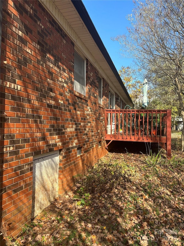 view of side of home featuring a wooden deck and brick siding