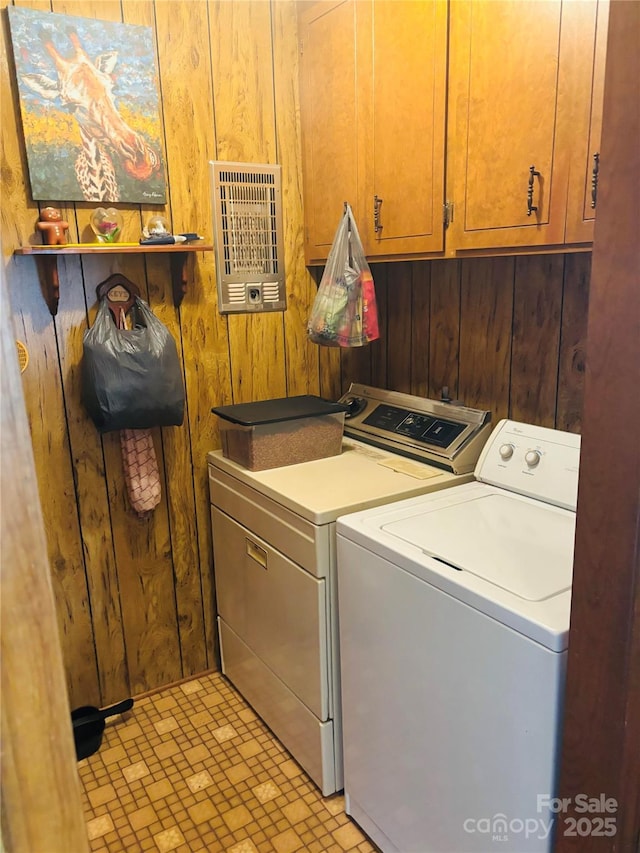 laundry room with separate washer and dryer, wooden walls, and cabinet space