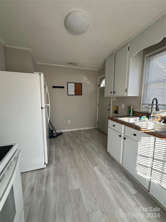 kitchen with white appliances, white cabinets, sink, light wood-type flooring, and a textured ceiling