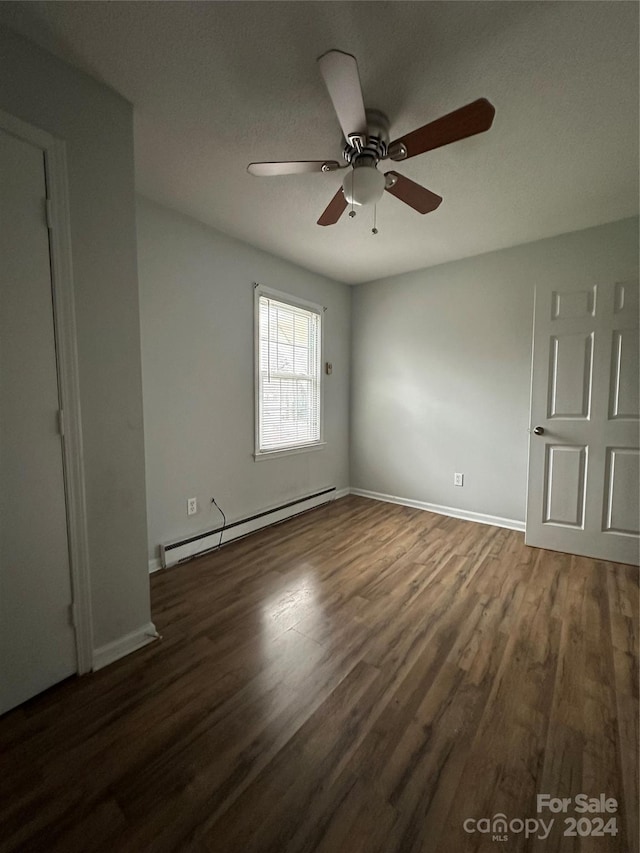 spare room featuring ceiling fan, dark wood-type flooring, and a baseboard radiator