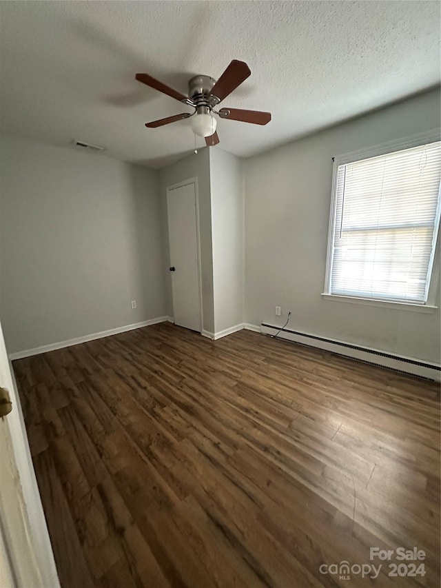 spare room with a textured ceiling, a baseboard radiator, ceiling fan, and dark wood-type flooring