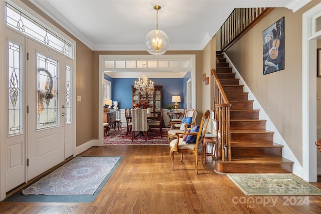 foyer entrance featuring hardwood / wood-style flooring, an inviting chandelier, and crown molding