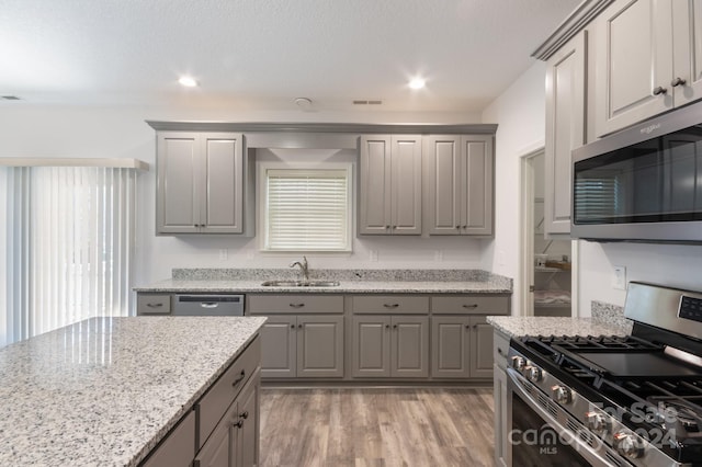 kitchen featuring sink, gray cabinets, light stone countertops, light wood-type flooring, and stainless steel appliances