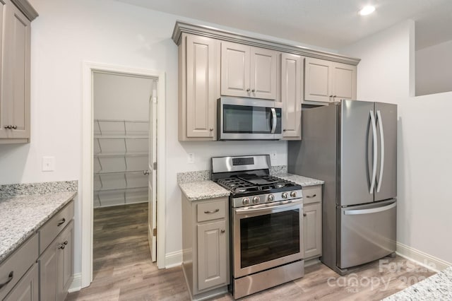 kitchen with light stone countertops, light wood-type flooring, and stainless steel appliances