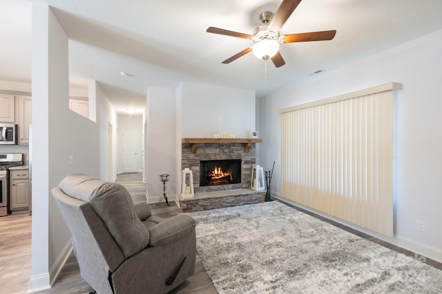 living room with a fireplace, light hardwood / wood-style flooring, and ceiling fan