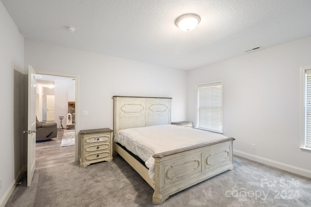 bedroom with light colored carpet and a textured ceiling