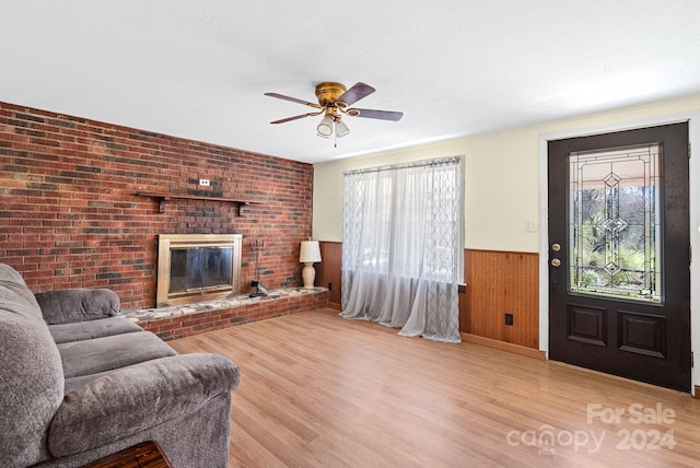 living room featuring ceiling fan, light hardwood / wood-style flooring, plenty of natural light, and wood walls