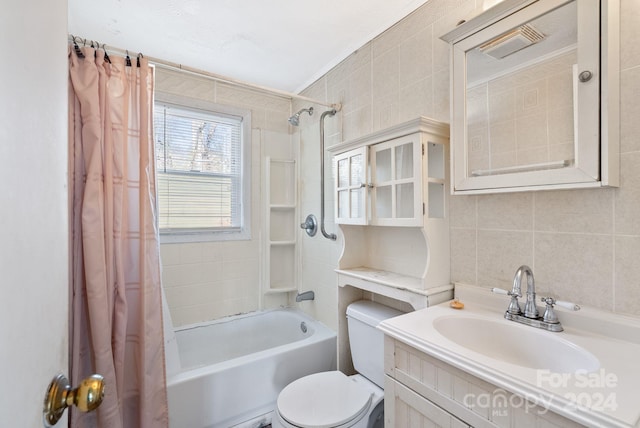 full bathroom with vanity, toilet, shower / bath combo with shower curtain, and tile walls