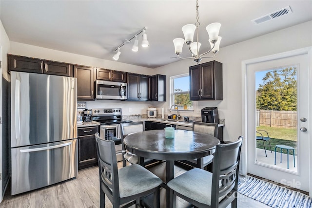 kitchen featuring dark brown cabinets, stainless steel appliances, pendant lighting, light hardwood / wood-style flooring, and a chandelier