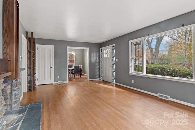 unfurnished living room with wood finished floors, visible vents, and baseboards