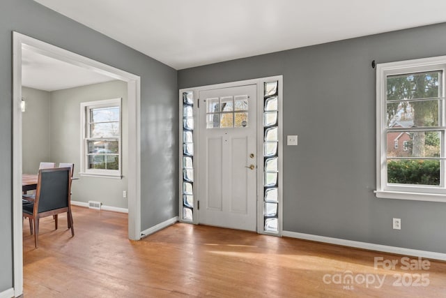 entryway with light wood-style flooring, baseboards, and a wealth of natural light