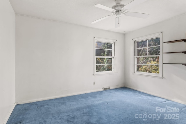 carpeted empty room with visible vents, baseboards, and ceiling fan