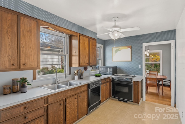 kitchen with a sink, black appliances, brown cabinetry, and light countertops