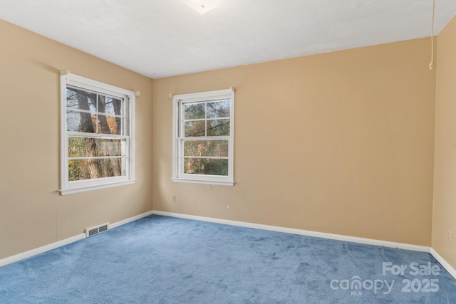 empty room featuring carpet flooring, baseboards, and visible vents