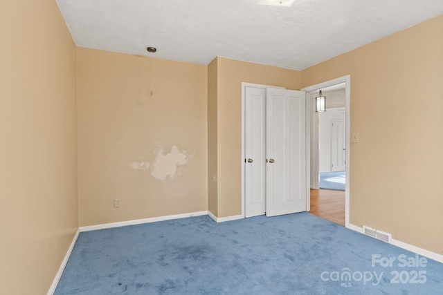 unfurnished bedroom featuring baseboards, visible vents, and carpet floors