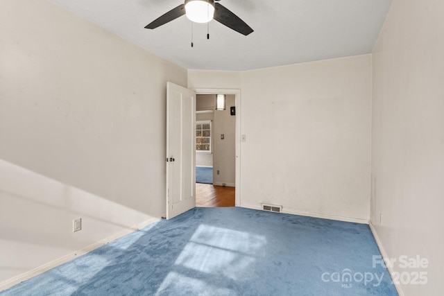 spare room with a ceiling fan, carpet, visible vents, and baseboards